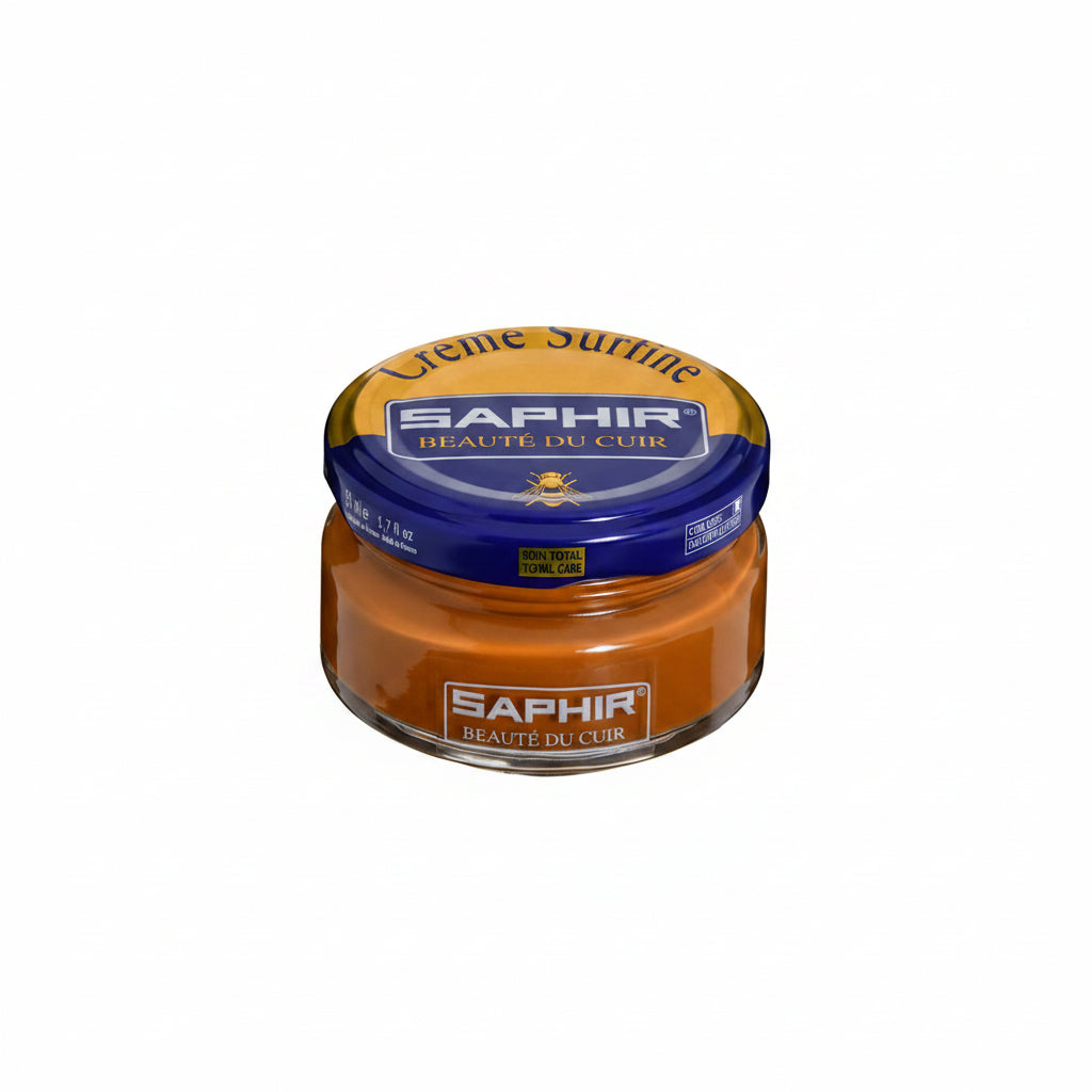 Saphir Crème Surfine hair styling cream in a round glass jar with a blue and gold lid and orange-brown cream visible inside.